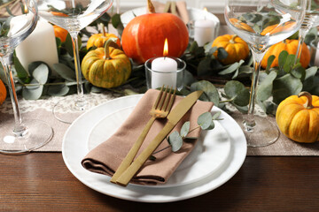 Beautiful autumn table setting. Plates, cutlery, glasses, pumpkins and floral decor