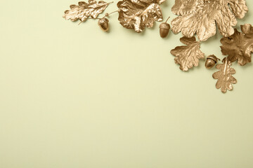 Golden oak leaves and acorns on beige background, flat lay with space for text. Autumn decor