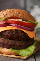 Tasty cheeseburger with patties on wooden table, closeup