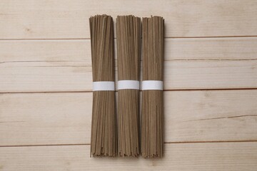 Uncooked buckwheat noodles (soba) on light wooden table, flat lay