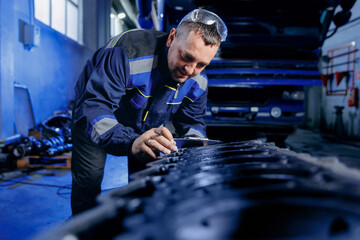 Mechanic checks problem of diesel engine from industrial truck in garage. Fix service repair cargo car concept