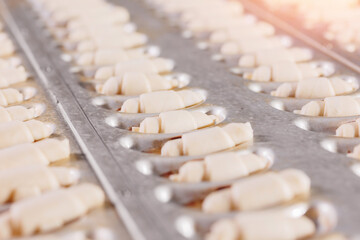 French croissants from puff pastry dough pieces in metal form. Food bakery industry production