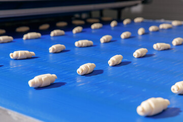 Concept smart modern technology in food industry. Process Production of French croissants, puff pastry dough pieces are automatically moved along line conveyor