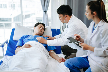 Two doctors talking to a patient lying in his bed with receiving saline solution in hospital .