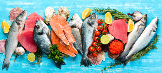Seafood background: salmon, tuna, caviar, oysters, dorado fish and shellfish on a blue wooden...