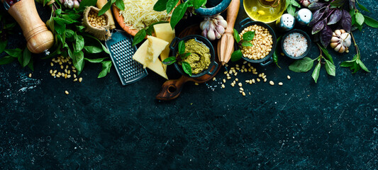 Traditional pesto sauce. Ingredients: Basil, pine nuts, Parmesan and olive oil. On a black stone background.