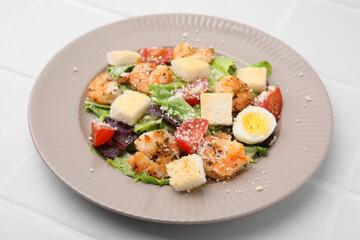 Fototapeta na wymiar Delicious Caesar salad with shrimps on white tiled table, closeup