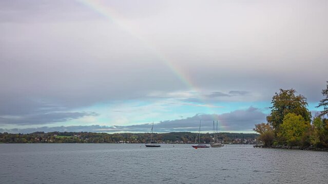 Rainbow over lake Attersee and sailboats, time lapse view