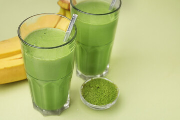 Glasses of tasty matcha smoothie and powder on pale green background, closeup. Space for text