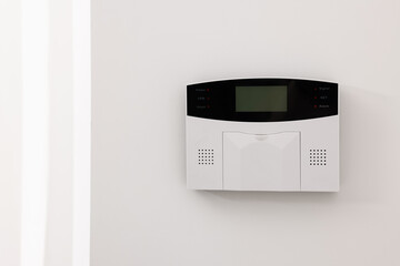 Home security alarm system on white wall indoors, space for text