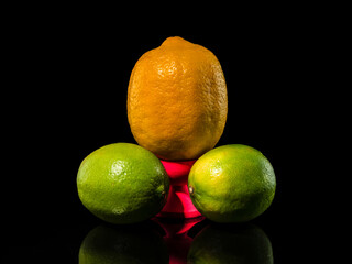 Composition with lemon and two limes on a black background