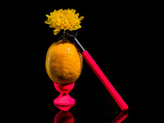 Composition with lemon and rake on a black background