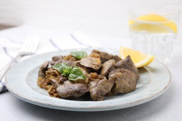 Delicious fried chicken liver with onion and basil on light table, closeup