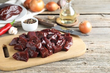 Cut raw beef liver and products on wooden table, space for text