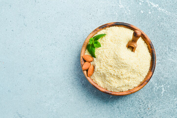 Almond flour in a wooden bowl. On a light stone background. Top view. Copy space.