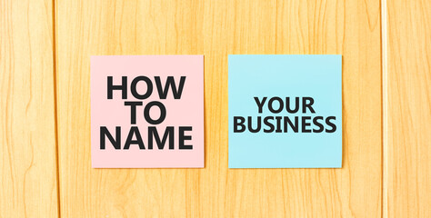 Inscription HOW TO NAME YOUR BUISINESS on pink and blue square sticky sticker on wooden wall