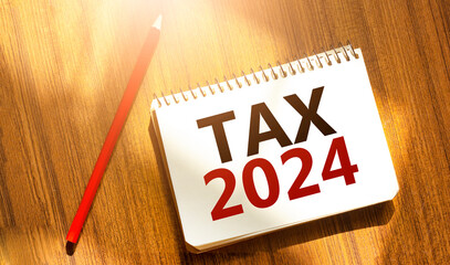 tax 2024 on notebook with red pencil on wooden background