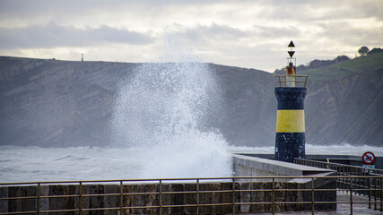 wave breaks against the lighthouse
