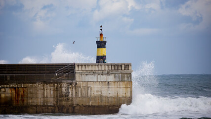 wave breaks against the lighthouse