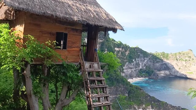 View from the "Rumah Pohon" near Diamond Beach, Nusa Penida, Bali. Wooden hut on the cliff of a mountain headland overlooking a diamond-shaped limestone rock.