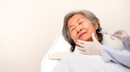 portrait asian senior woman lying on couch in clinic,closed eyes,cosmetologist hands in gloves...
