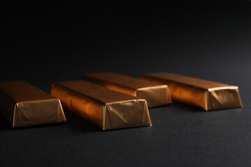 Chocolates in golden foil on black background, close up