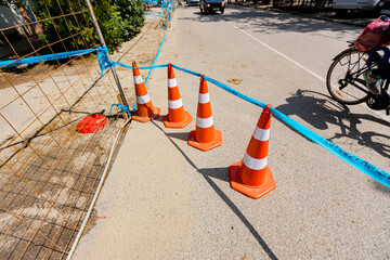 Few traffic cones tied, connected, with blue warning tape