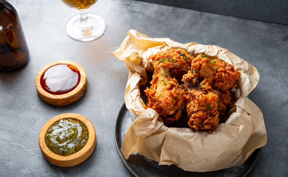 Bowl of deep fried chicken wings with bbq souse and beer on gray table