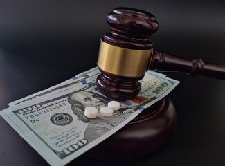 Wooden judge gavel and drug pills on background of cash in dollars