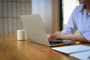 Closeup image of businesswoman hands typing on laptop surfing the internet or online working