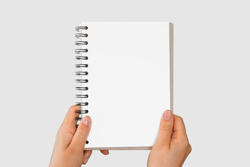 Female Hand Holding Notepad with Blank Page Isolated On Gray Neutral Studio Background. Close Up....