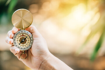 With a hand holding a compass in a natural forest setting find your direction and explore the possibilities. Ample copy space allows for conveying travel lifestyle and successful business concepts.