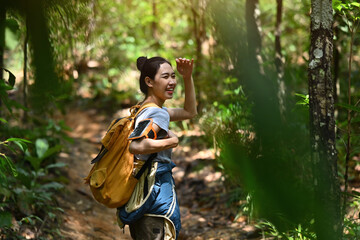 Smiling female traveller with backpack trekking in forest, exploring nature. Traveling, trekking...