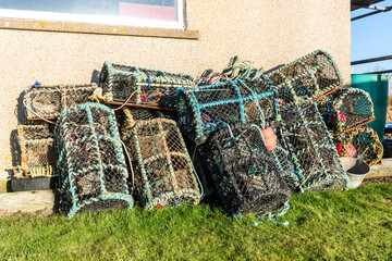 Traditional lobster pots or crab pots stacked up on the quayside in the fishing village of Caithness, Scotland - 675756868