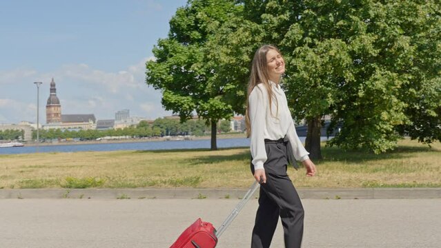Happy businesswoman arrived to Riga city, walking with luggage