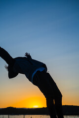 Young man doing sport activity at the beach during sunset.Shoulder roll, sportive dangerous trick.