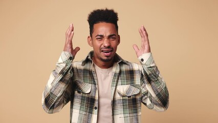 Young displeased man of African American ethnicity he wear shirt casual clothes ask what hears fake news propaganda has some problems gesticulating with hands isolated on plain beige brown background - Powered by Adobe