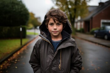 A portrait of a boy in a raincoat in the street.