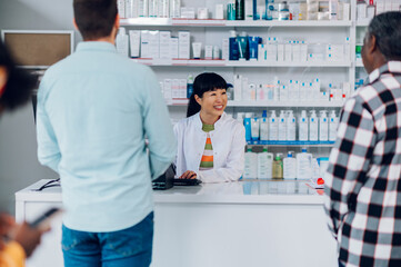 Obraz premium Japanese woman pharmacist selling drugs to a customer in a pharmacy