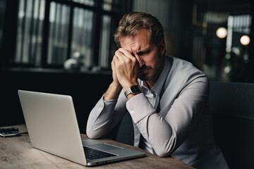 Project manager or male businessman fails at work and finances go bankrupt Sitting and working on a computer or laptop causes stress and headaches at work.