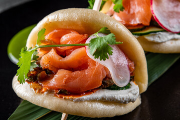 Asian burger, gua bao, made with Chinese brioche, salmon and vegetables on plate