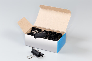 Black binder clips for paper in the open paperboard box