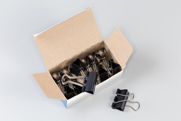 Black binder clips for paper in the open paperboard box