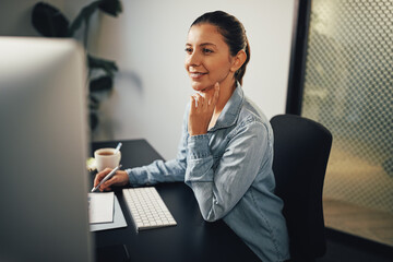 Smiling businesswoman taking notes and working on a computer