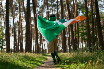 Little boy dancing with large flag of Ireland on Saint Patricks Day festival outdoors