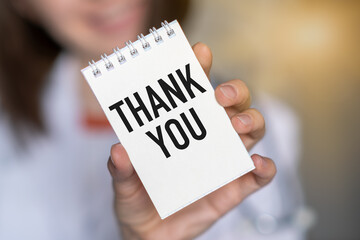 Close-up of woman holding a sticky note with text Thank You a smiley face