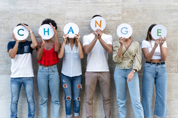 A group of diverse individuals standing together, each holding up a letter to collectively spell out the word 'CHANGE'.