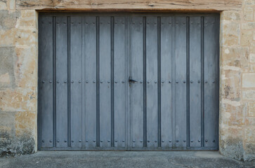 Front view of antique large double doors with blue wood texture and metallic forge vintage handle...