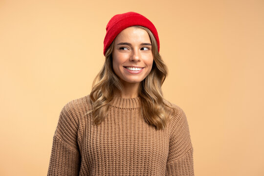 Portrait of young smiling woman wearing red hipster hat and stylish winter sweater looking away