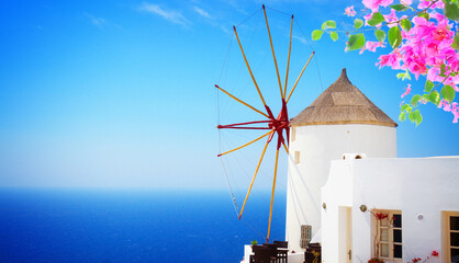 windmill of Oia at sunny day close up, Santorini with flowers